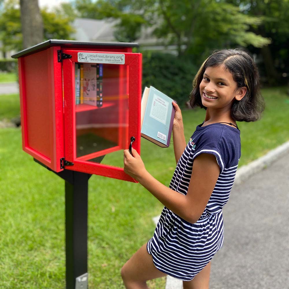 young female child opening the door to a little free library